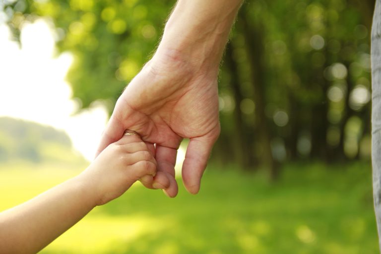 Closeup of parent hold Child's hand while walking