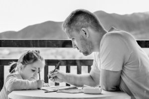 Father and daughter are drawing on paper together