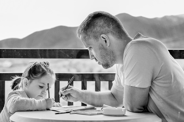 Father and daughter are drawing on paper together
