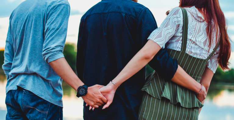 A man holding his male friend, girl friend hand.
