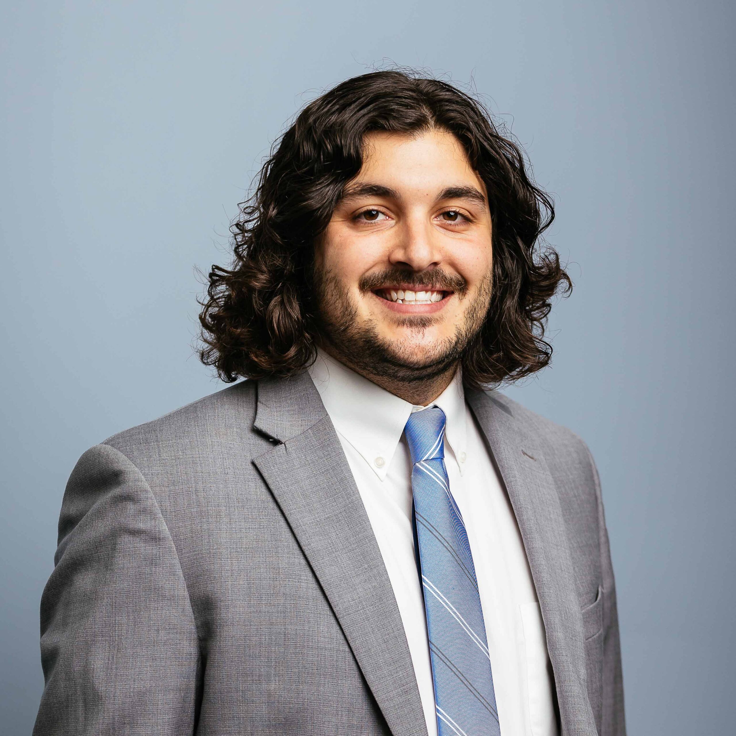 Man in gray suit with black curly hair